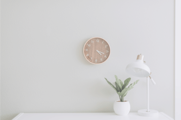 desk with clock plant and lamp