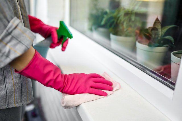 Person wiping windowsill with cloth